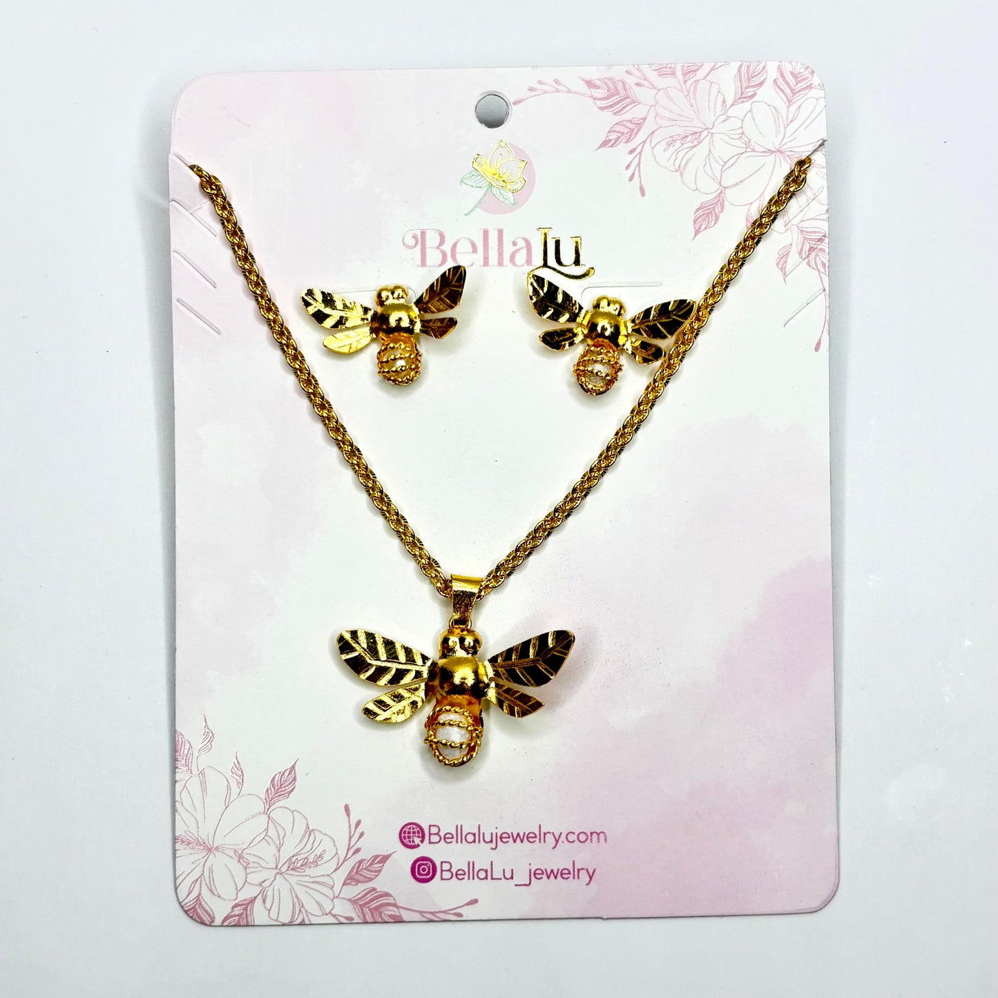 Gold bee necklace and earrings set on a Bella Lu branded card with floral design.