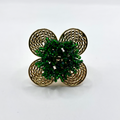 A handcrafted bronze ring with a gold plated design, featuring a flower shape with green beads and a textured pattern.