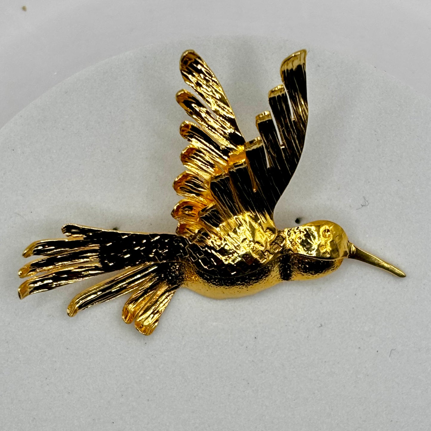 Close-up of an elegant hummingbird fancy pin brooch with sparkling gemstone details and vibrant colors.