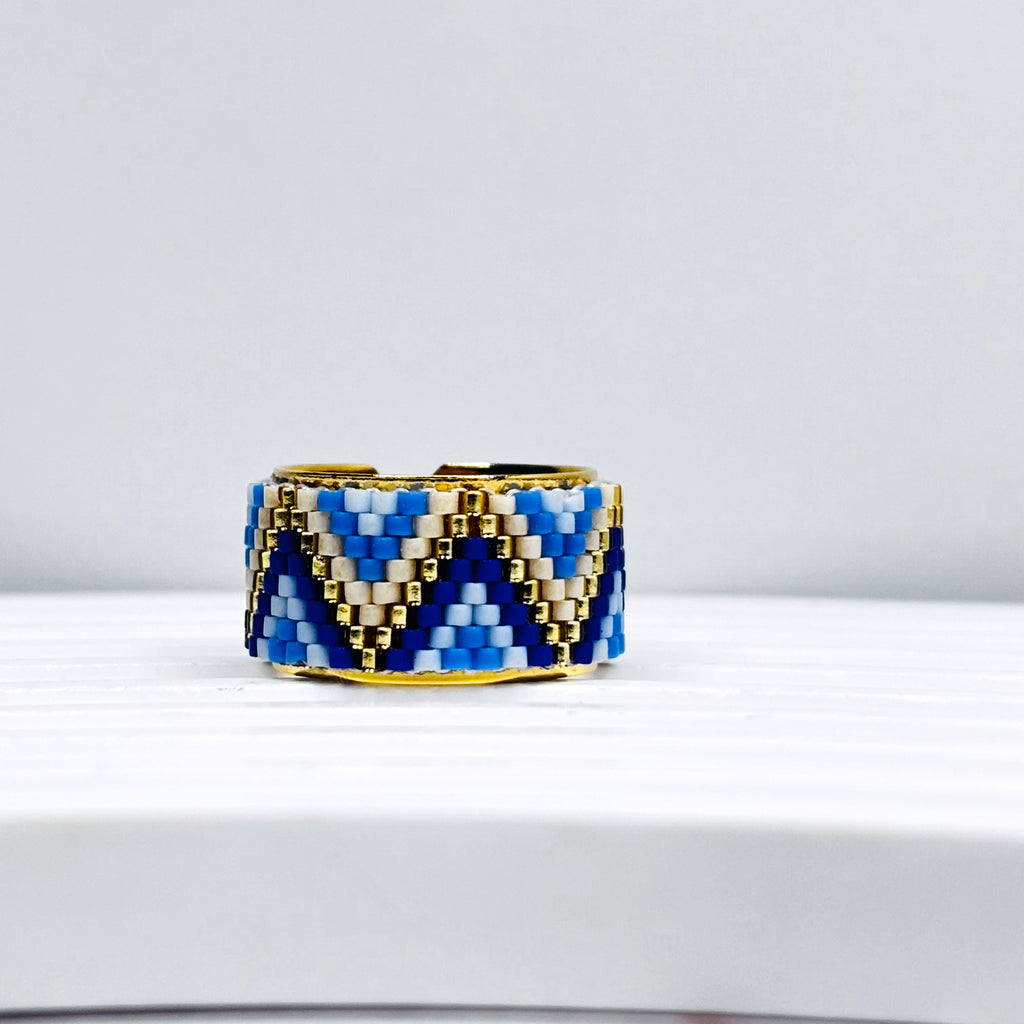 A handmade beaded ring with a geometric pattern, featuring a triangle shape design in blue and gold colors.