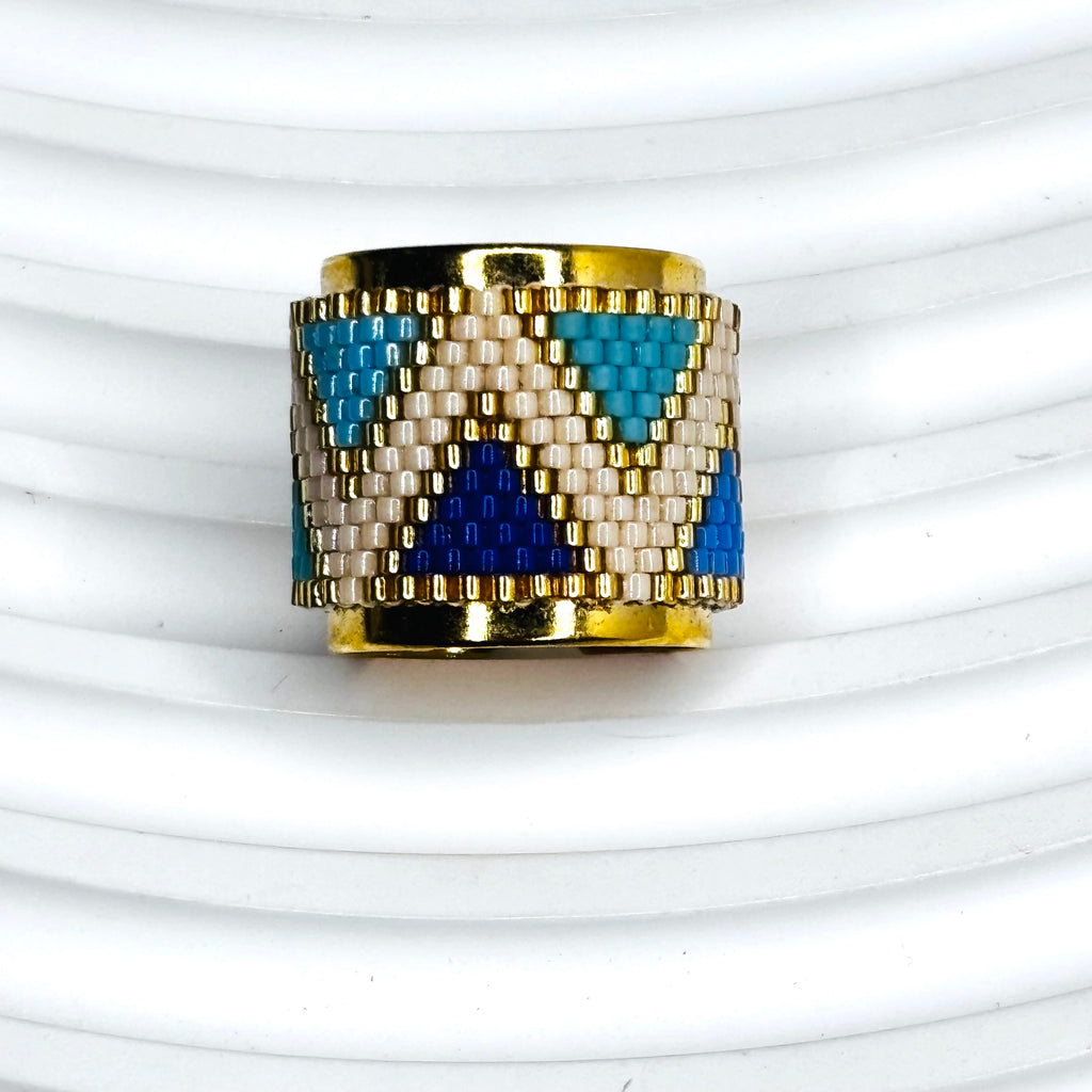 Gold ring with blue and white pattern on a white background