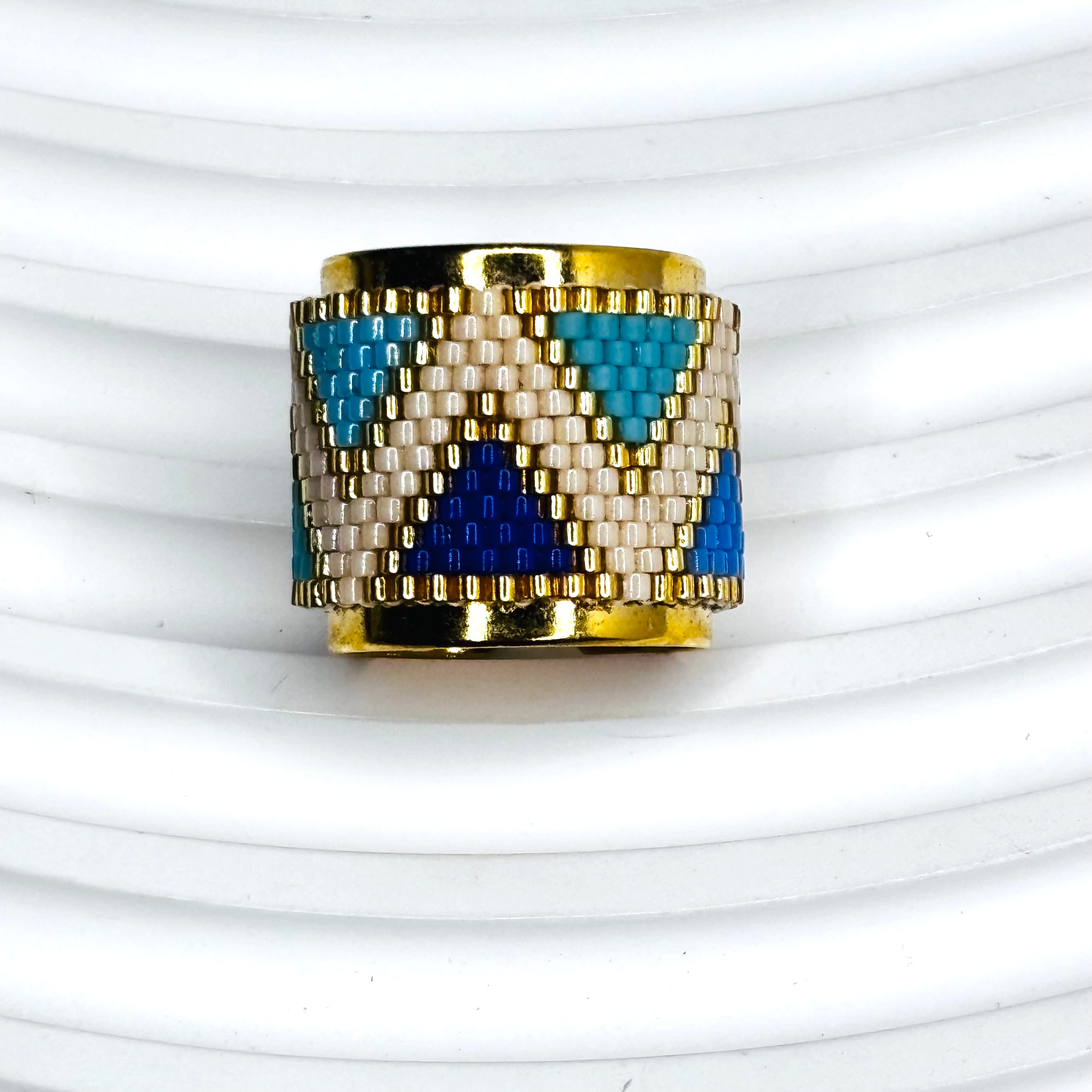 Gold ring with blue and white pattern on a white background