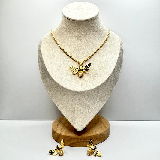 Gold necklace  bee and earrings on a mannequin bust with a plain background