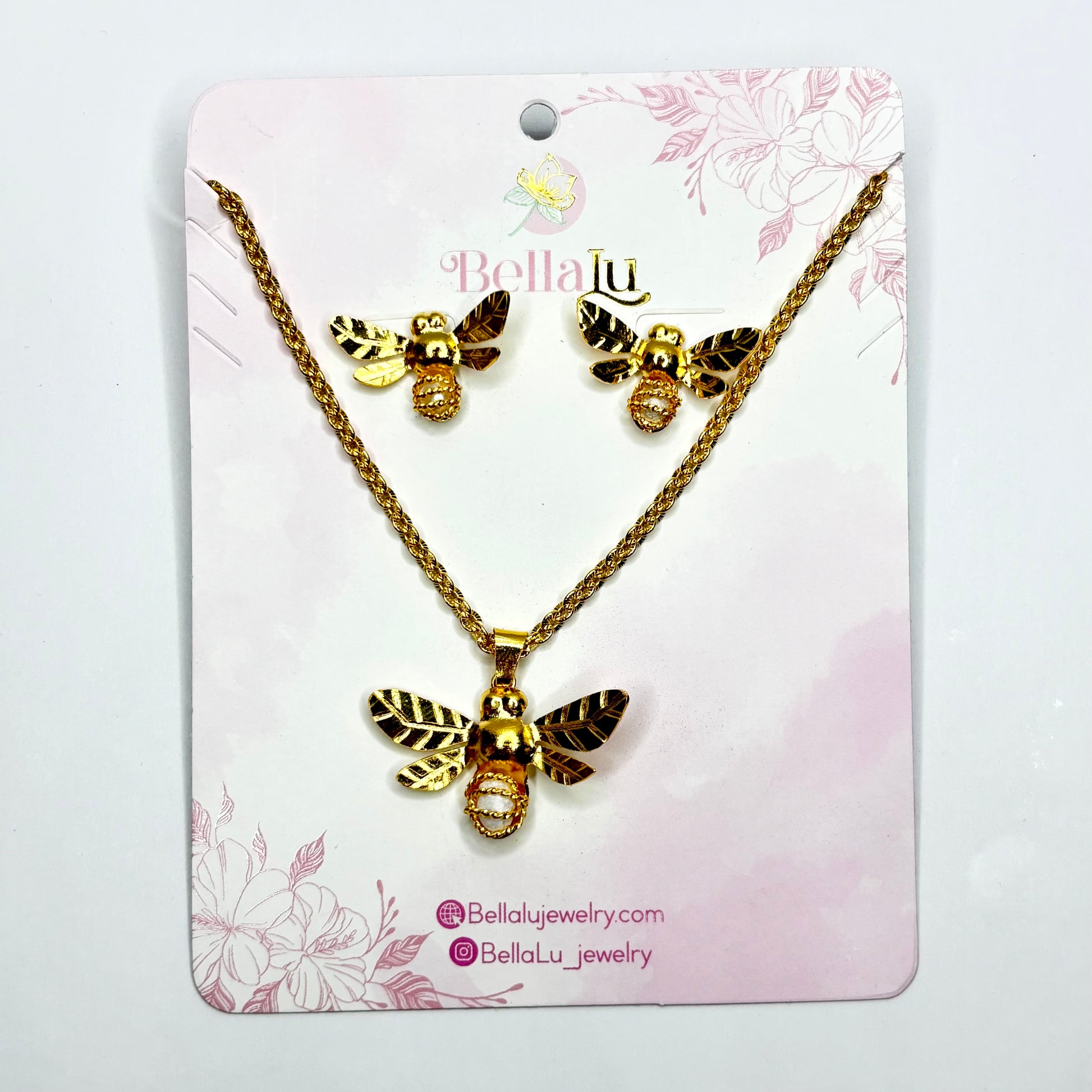 Gold bee necklace and earrings set on a Bella Lu branded card with floral design.