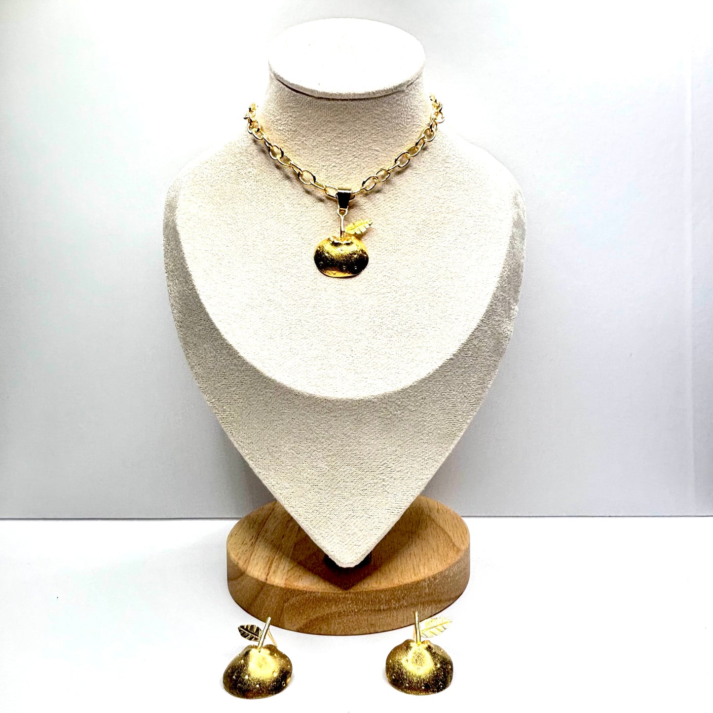 Gold necklace pear and earrings on a mannequin bust with a white background