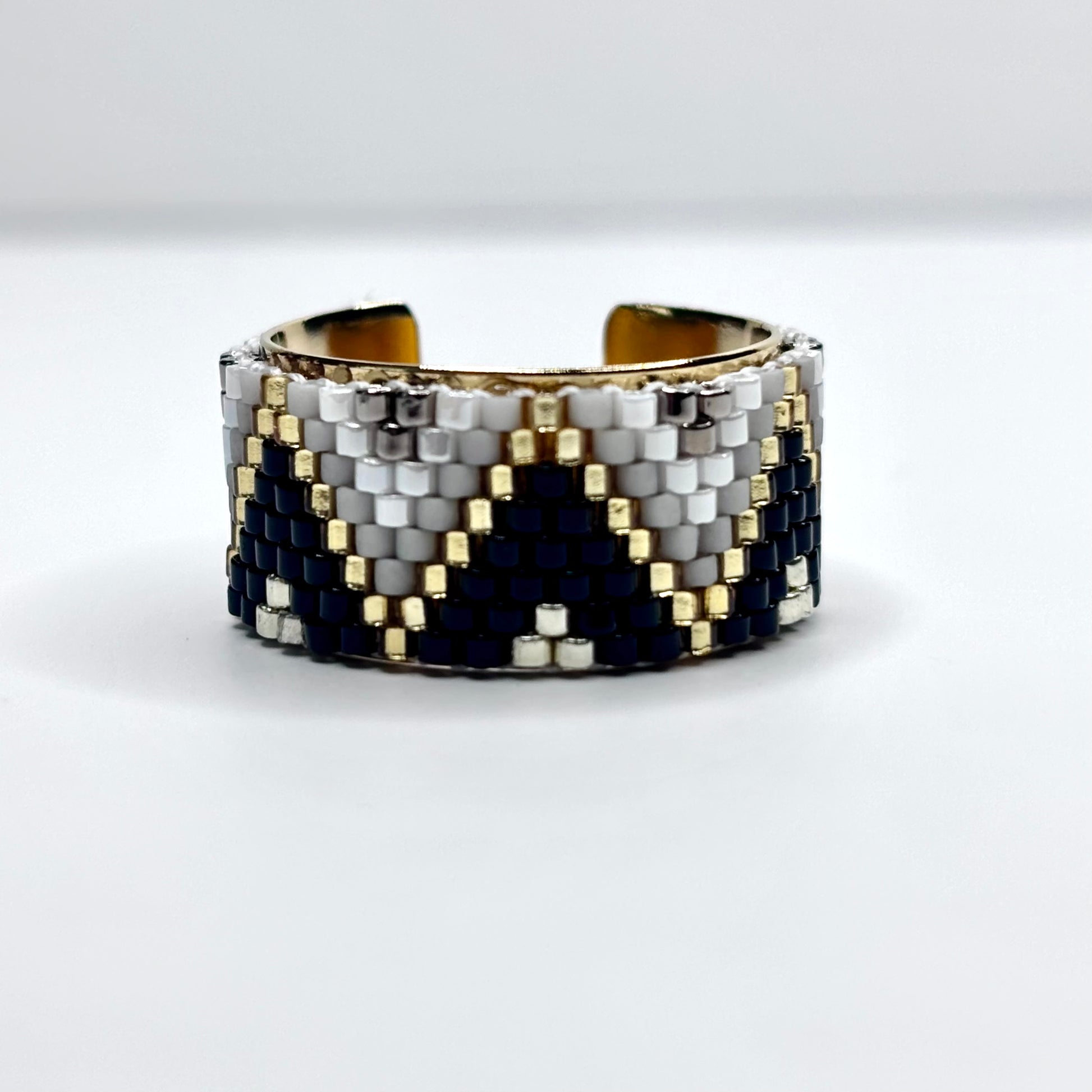 Beaded cuff bracelet with black, white, and gold pattern on a white background