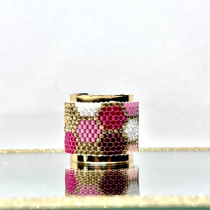 Decorative candle holder with pink and gold design on a reflective surface