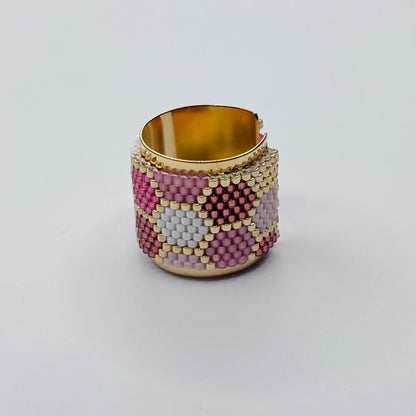 Beaded ring with gold trim on a light gray background