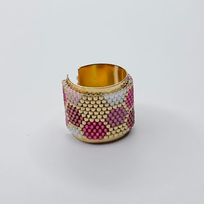 Beaded cuff bracelet with gold accents on a light gray background
