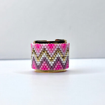 Beaded cuff bracelet with pink, gold, and white pattern on a white background