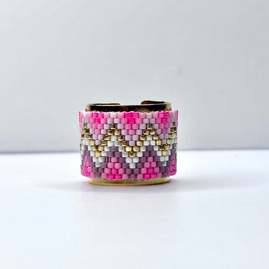 Beaded cuff bracelet with pink, gold, and white pattern on a white background