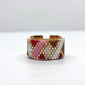 Beaded bracelet with pink, white, and gold pattern on a white background