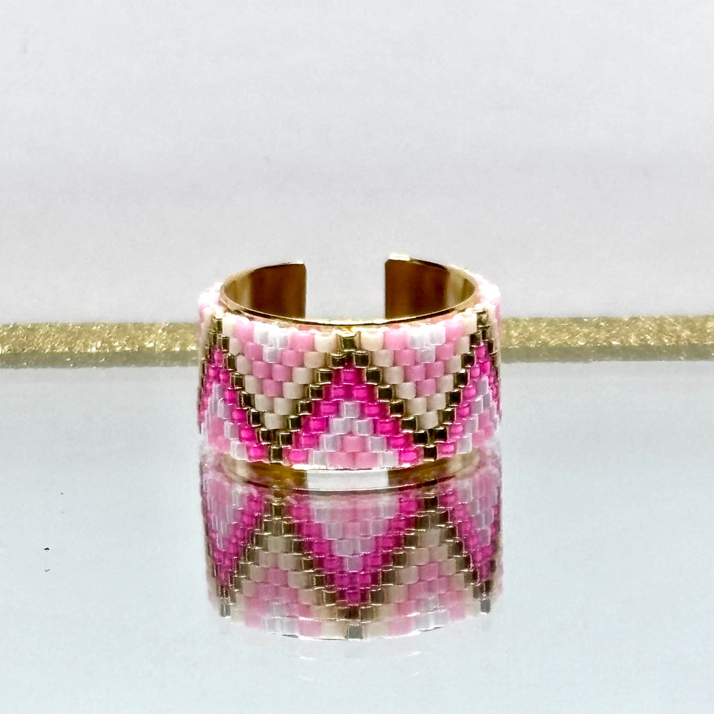 Beaded ring with pink, white, and gold pattern on a white background