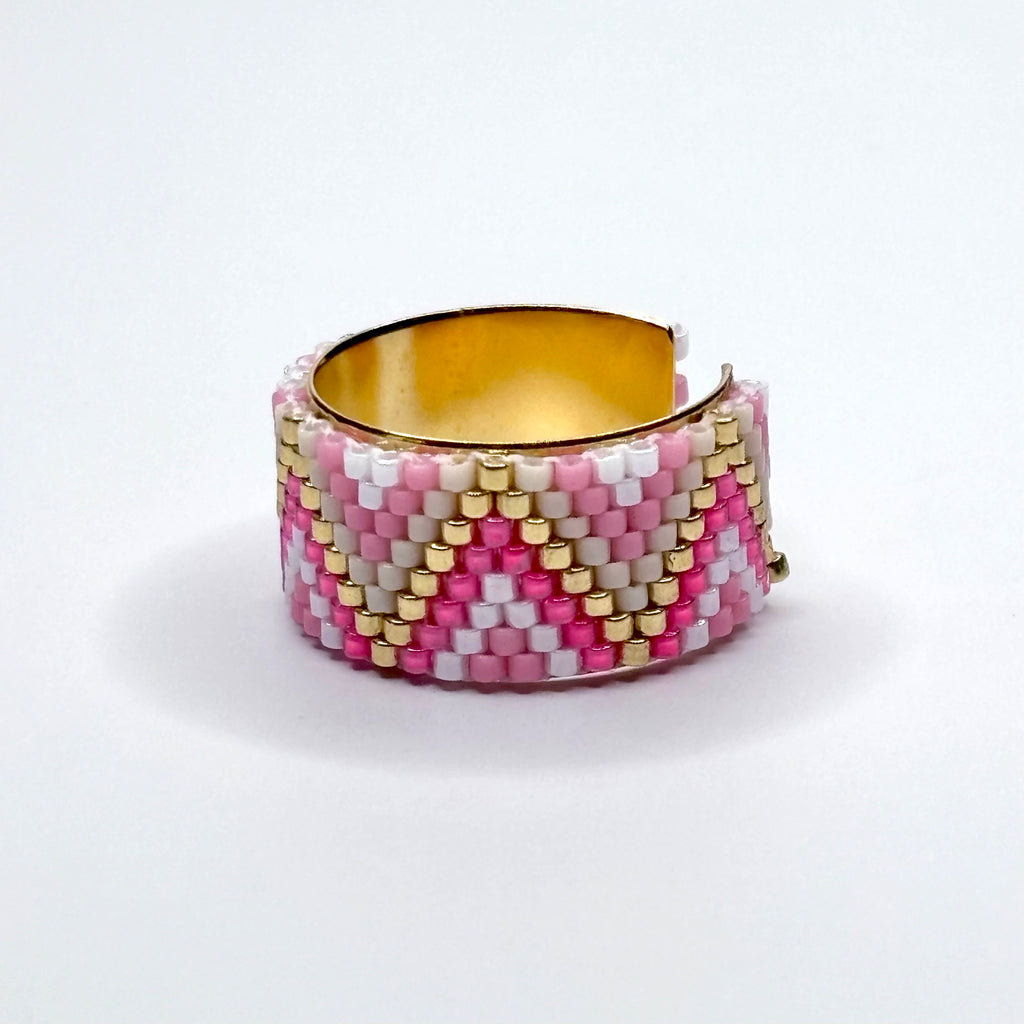 Beaded ring with pink, white, and gold pattern on a white background