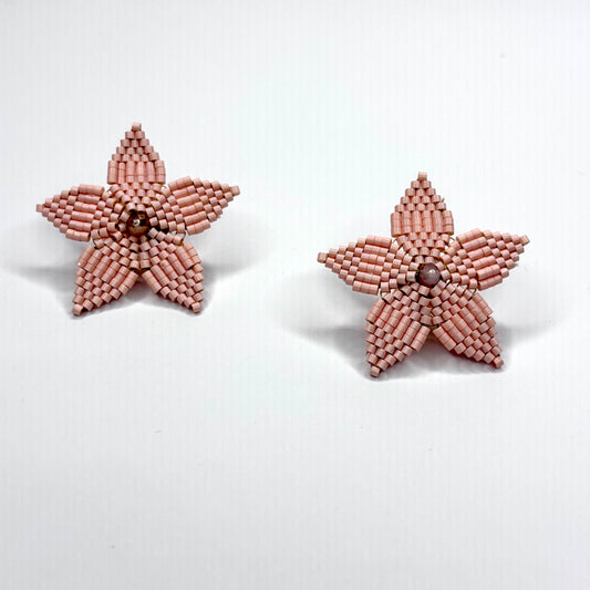 Star-shaped earrings made of pink beads on a white background