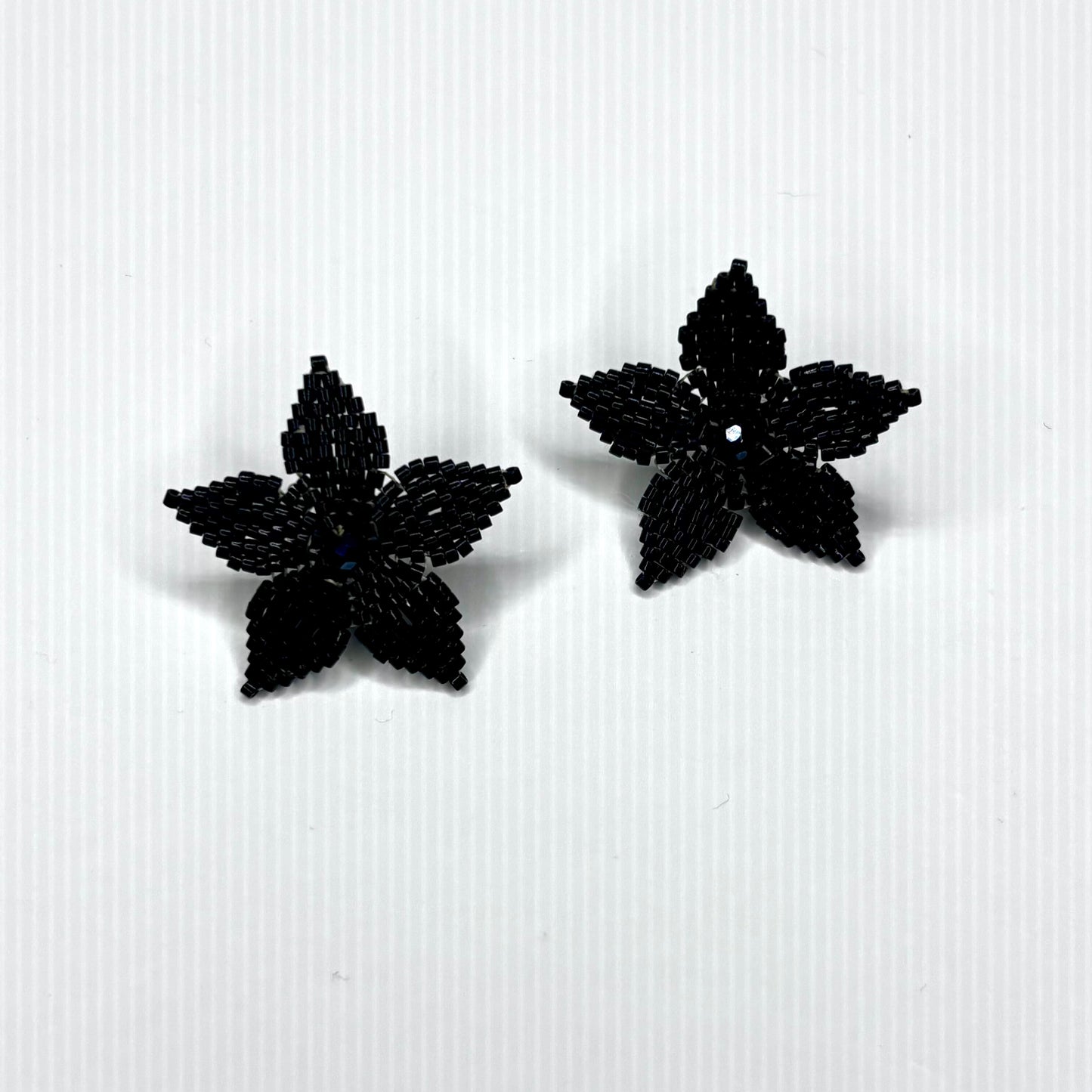 Black beaded flower earrings on a white background