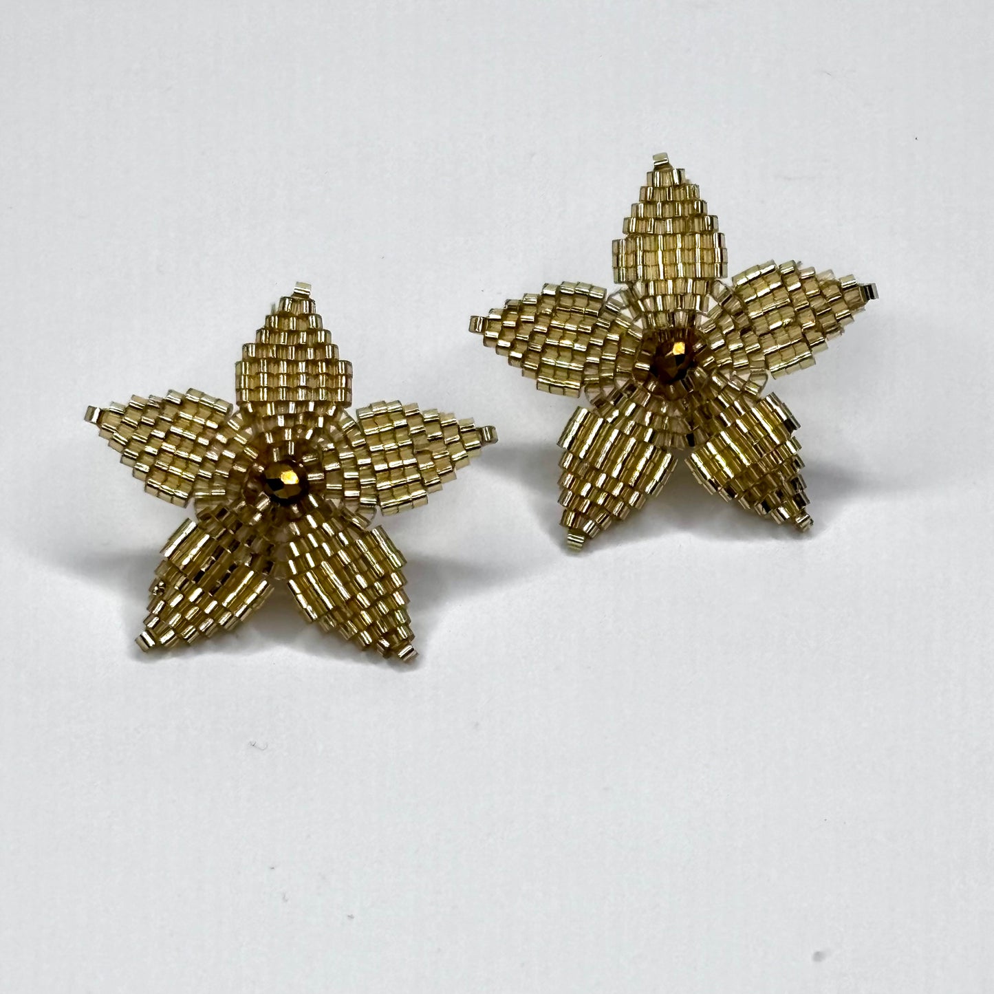 Pair of gold starfish-shaped earrings on a white background