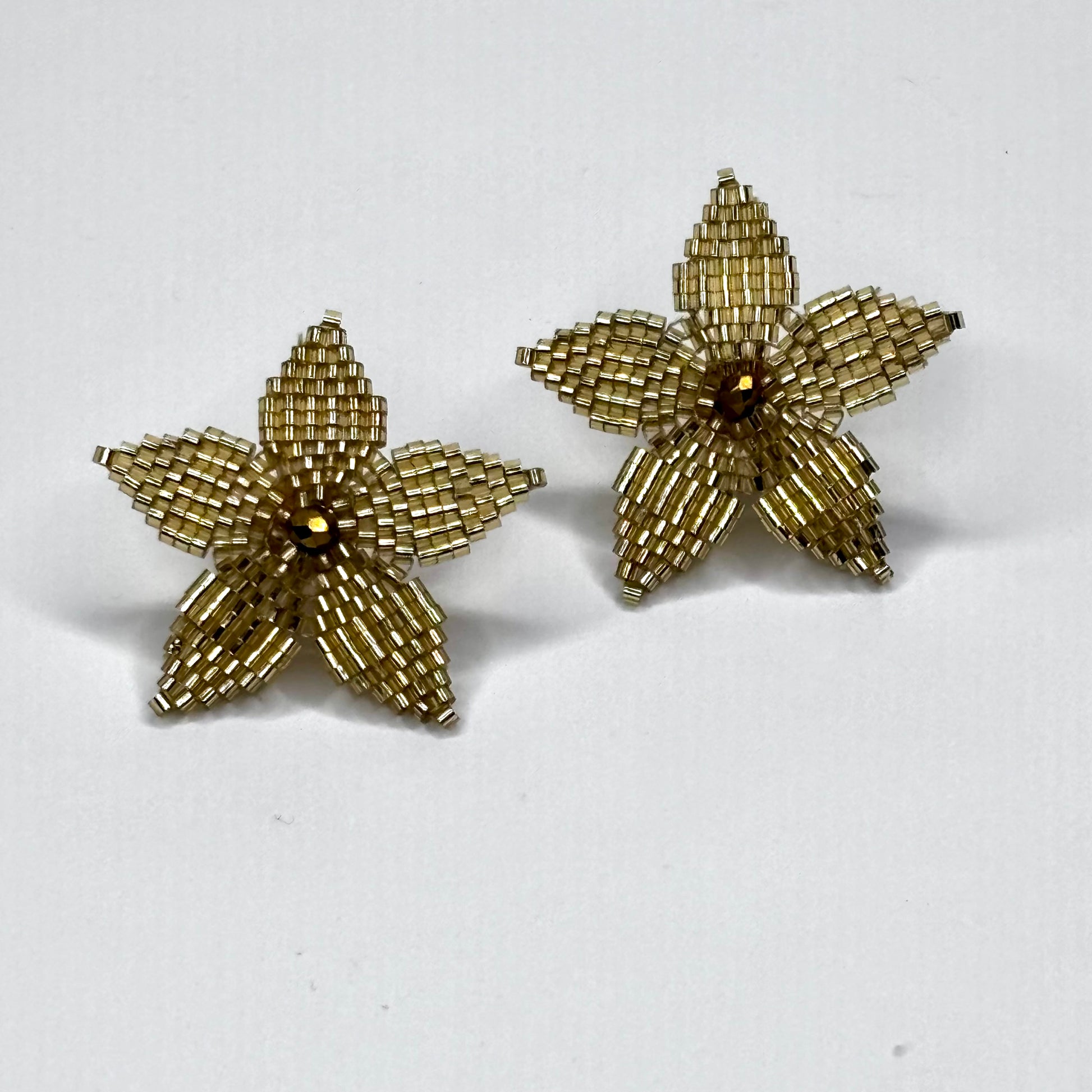 Pair of gold starfish-shaped earrings on a white background