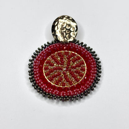 Decorative pendant with red and gold design on a white background