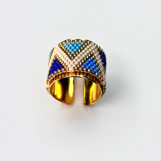 Gold ring with blue and white pattern on a white background