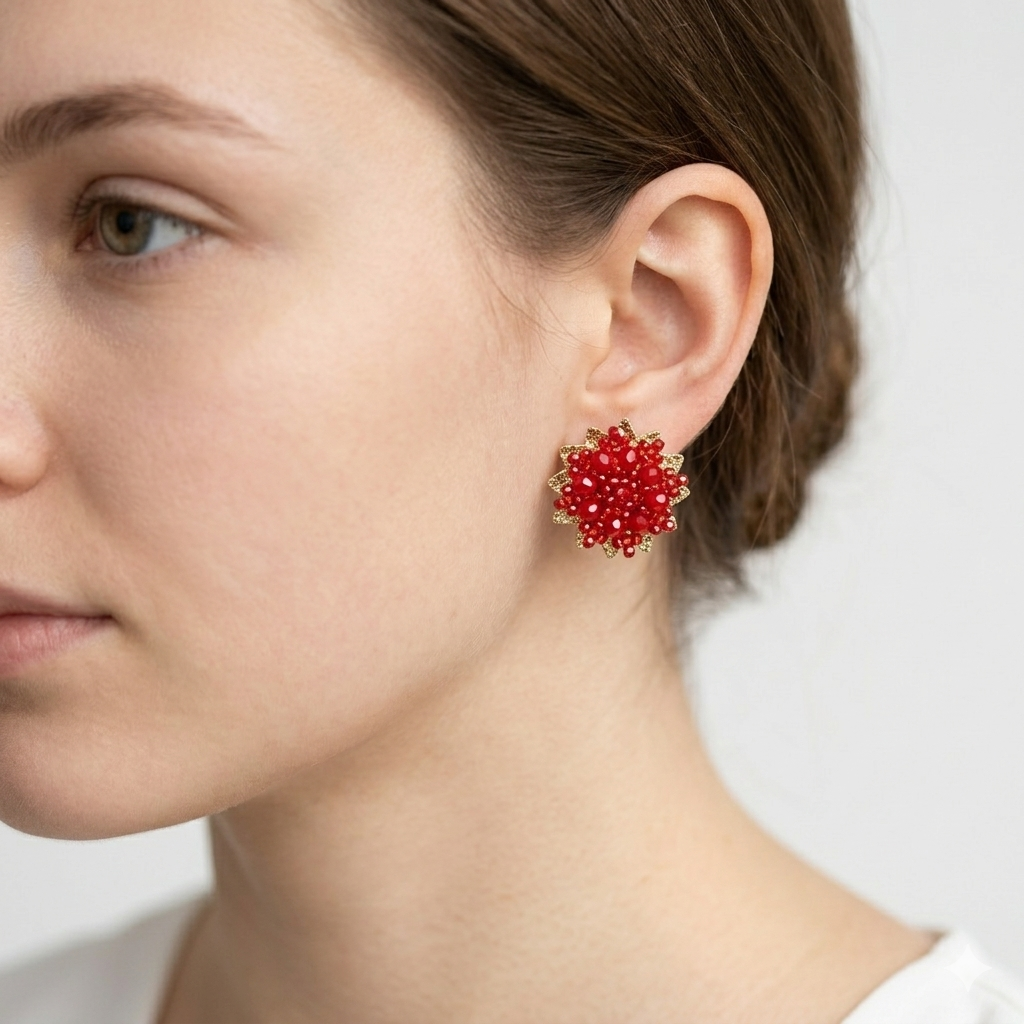 Close-up of a woman wearing red beaded earrings on a plain background