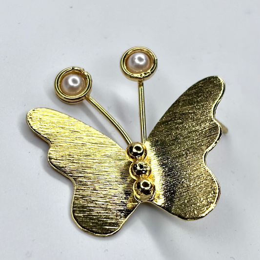 Gold butterfly earring with pearl accents on a light gray background