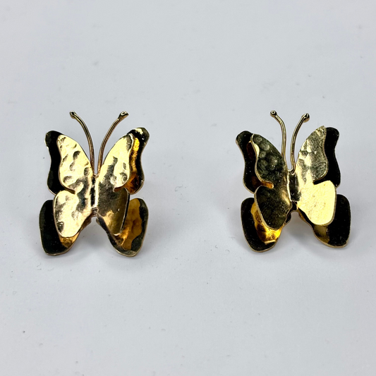 Gold butterfly earrings on a light gray background