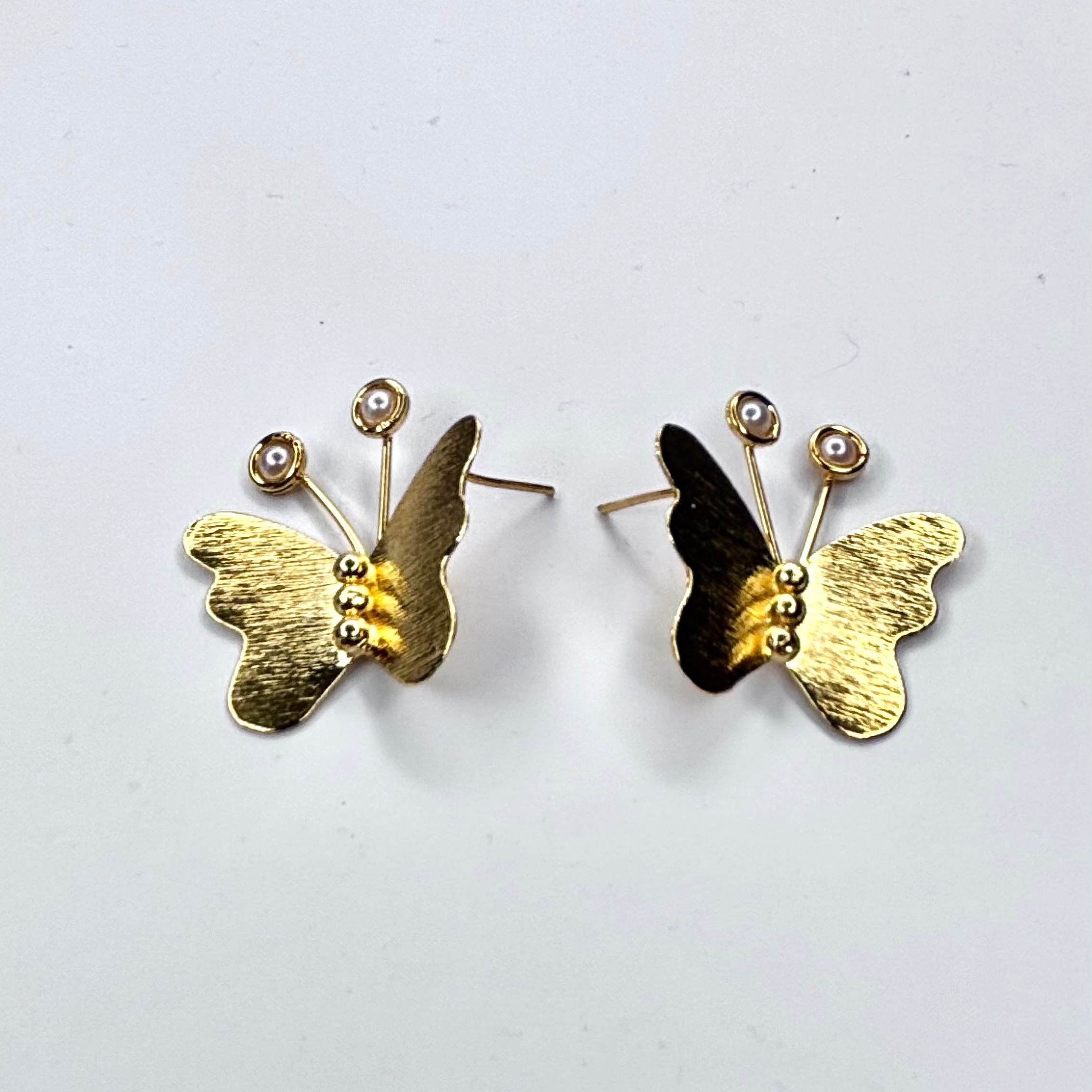 Gold butterfly earrings on a white background