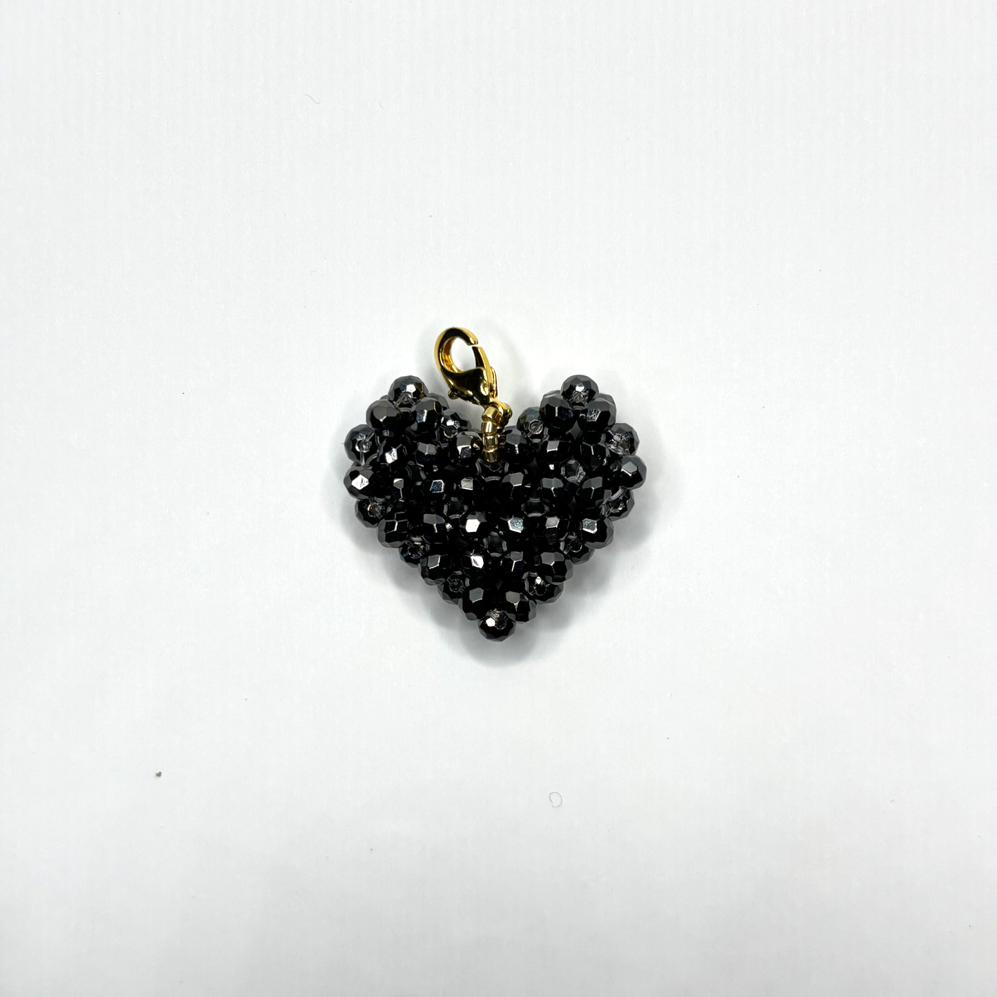 Heart-shaped black beaded pendant with gold chain on a white background