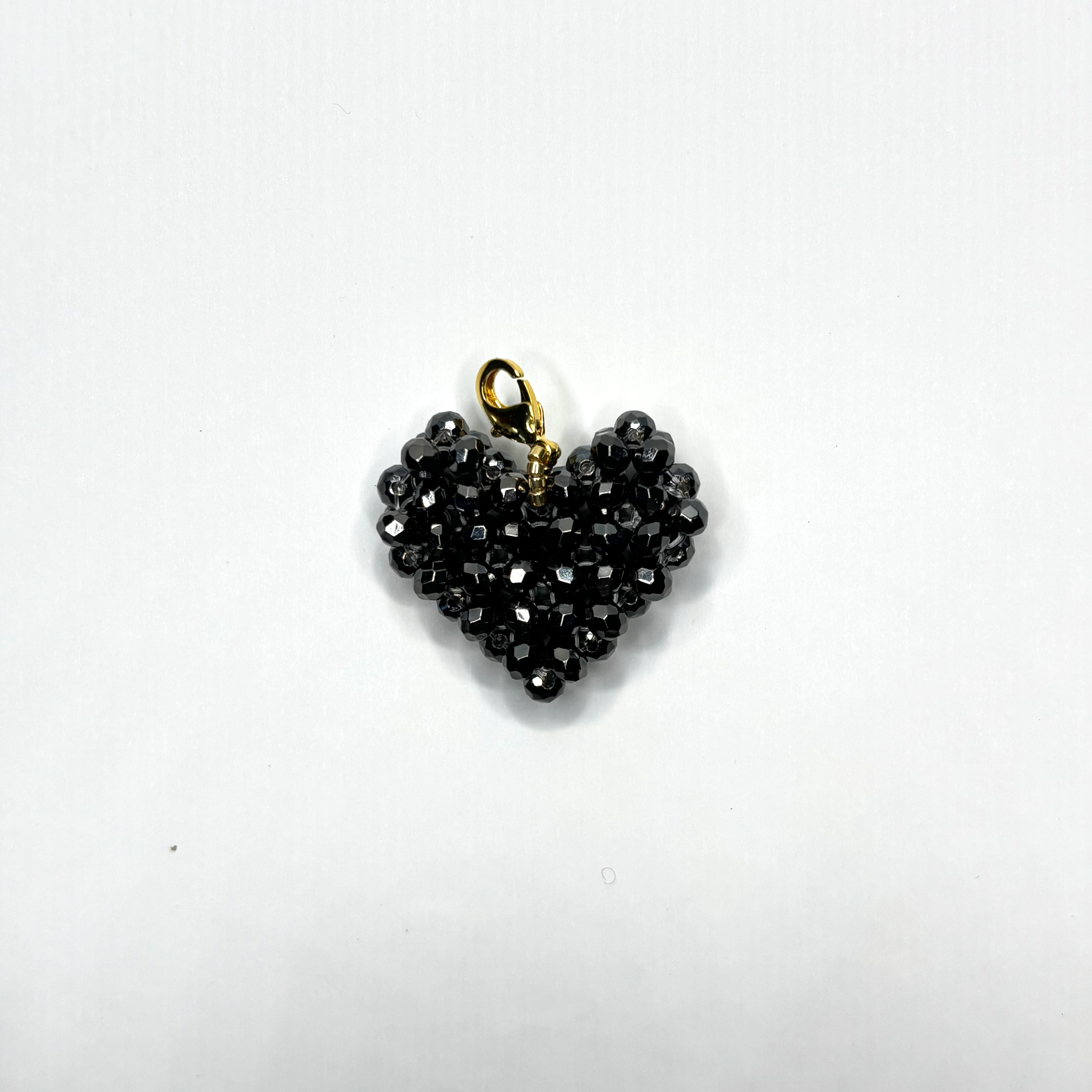 Heart-shaped black beaded pendant with gold chain on a white background