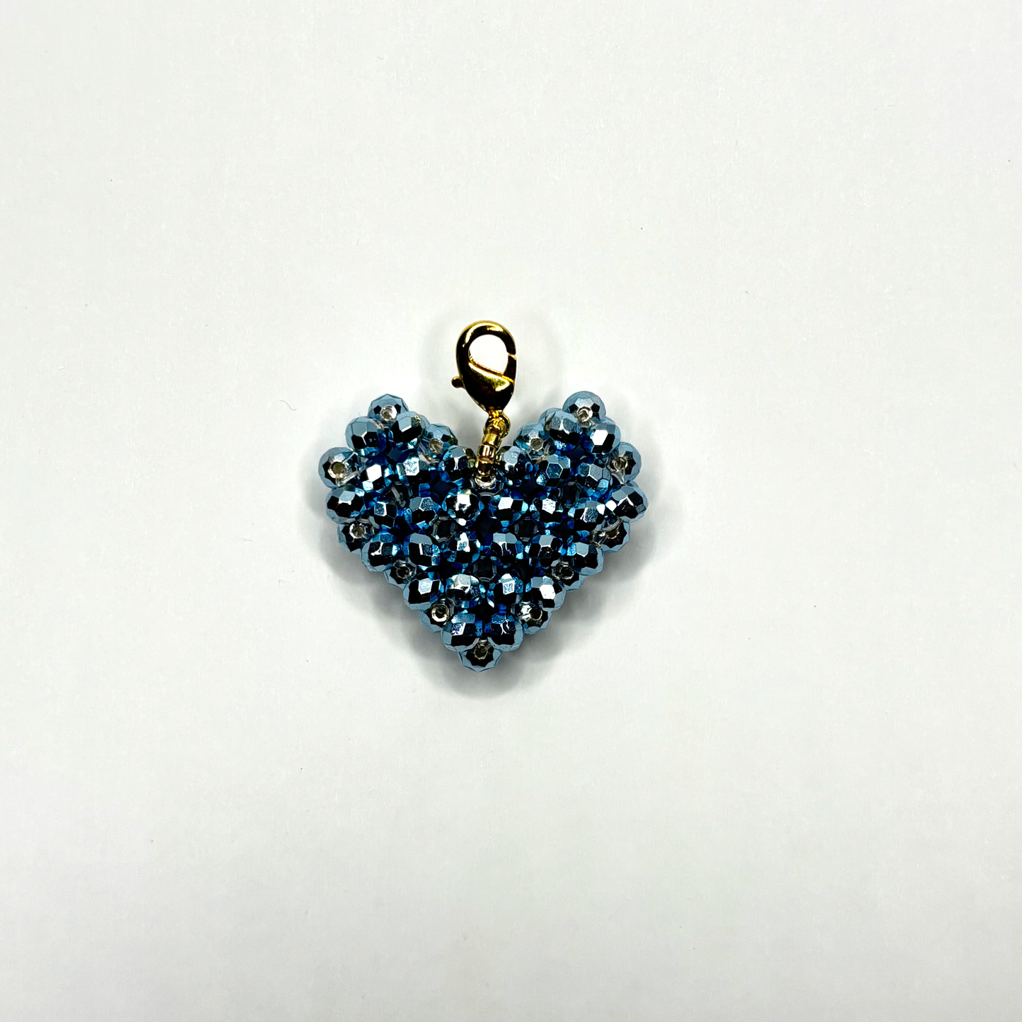 Heart-shaped blue beaded pendant on a white background
