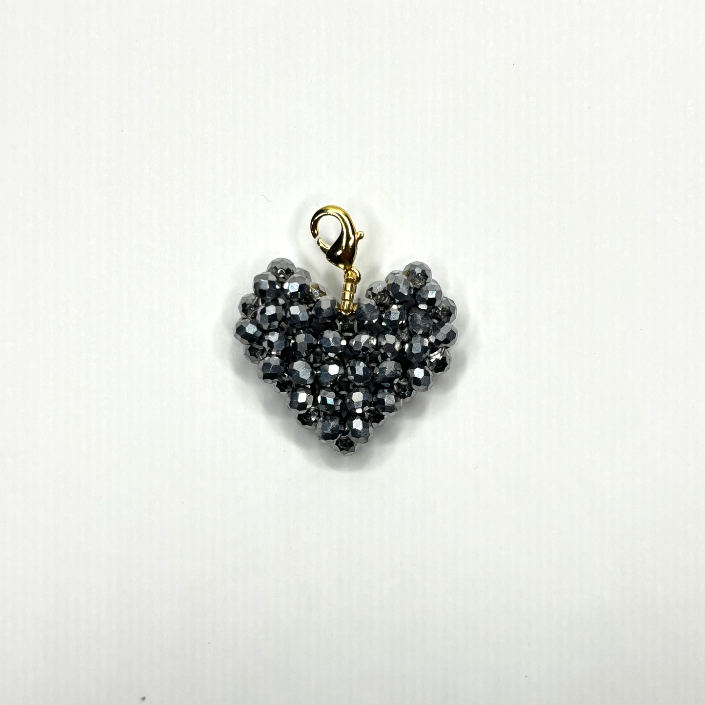 Heart-shaped pendant with black beads and gold clasp on a white background