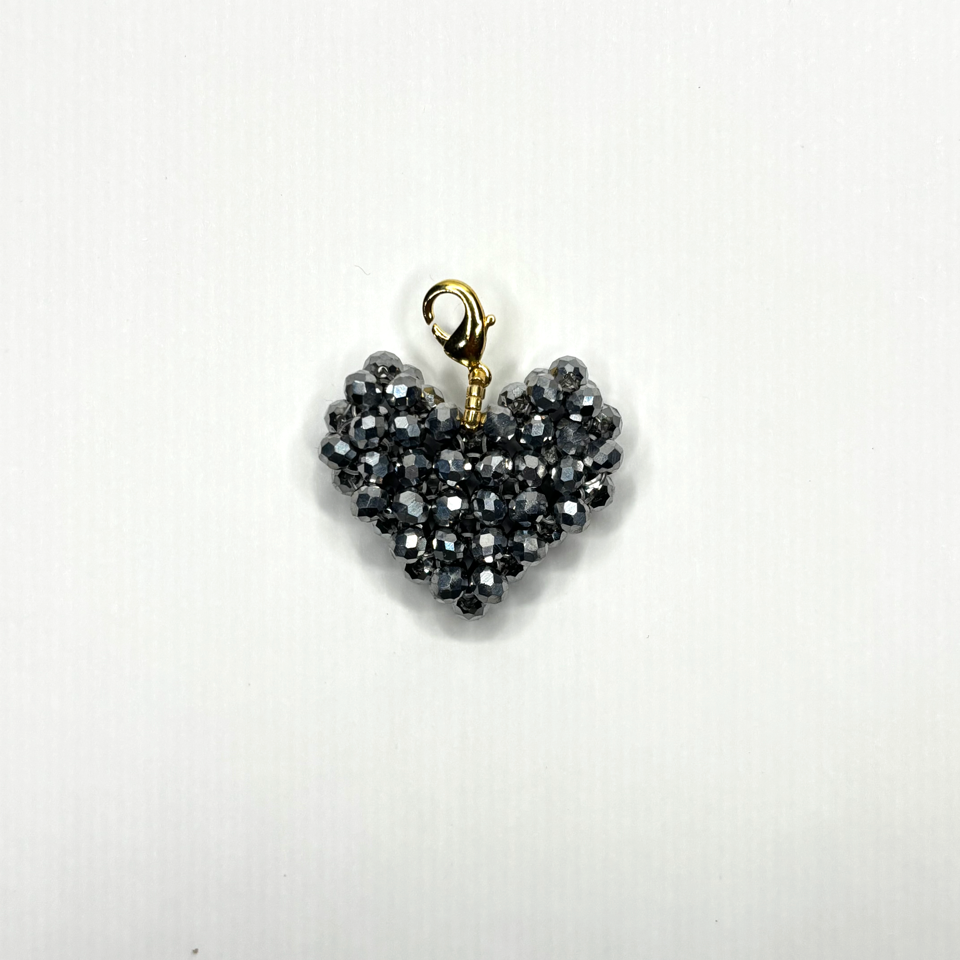 Heart-shaped pendant with black beads and gold clasp on a white background