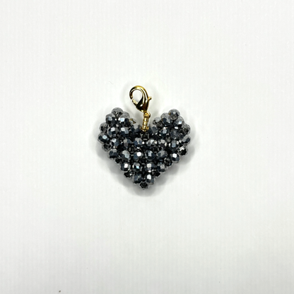 Heart-shaped pendant with black beads and gold clasp on a white background