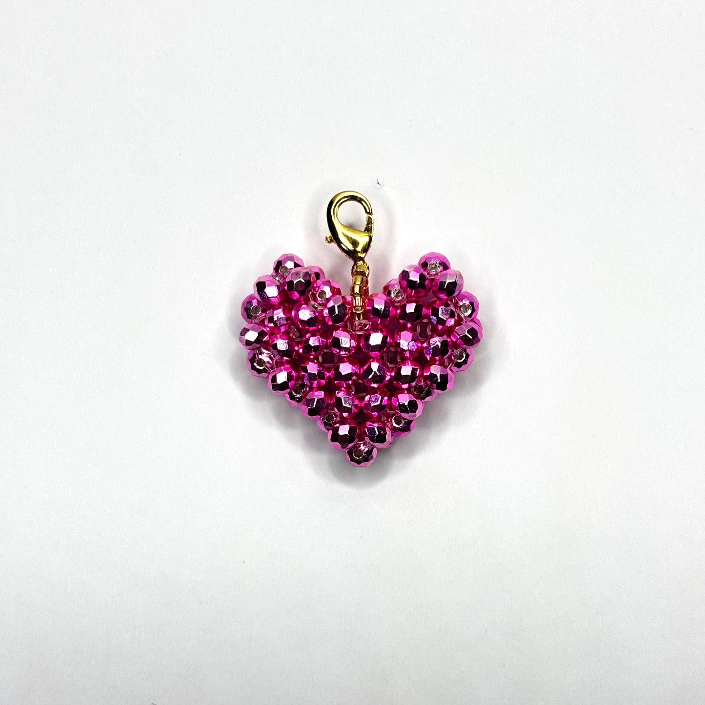 Pink beaded heart charm with gold clasp on a white background