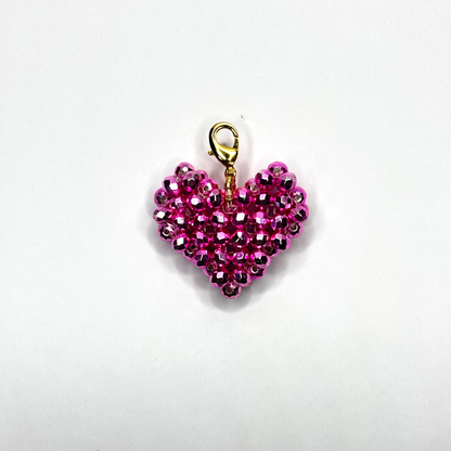 Pink beaded heart charm with gold clasp on a white background