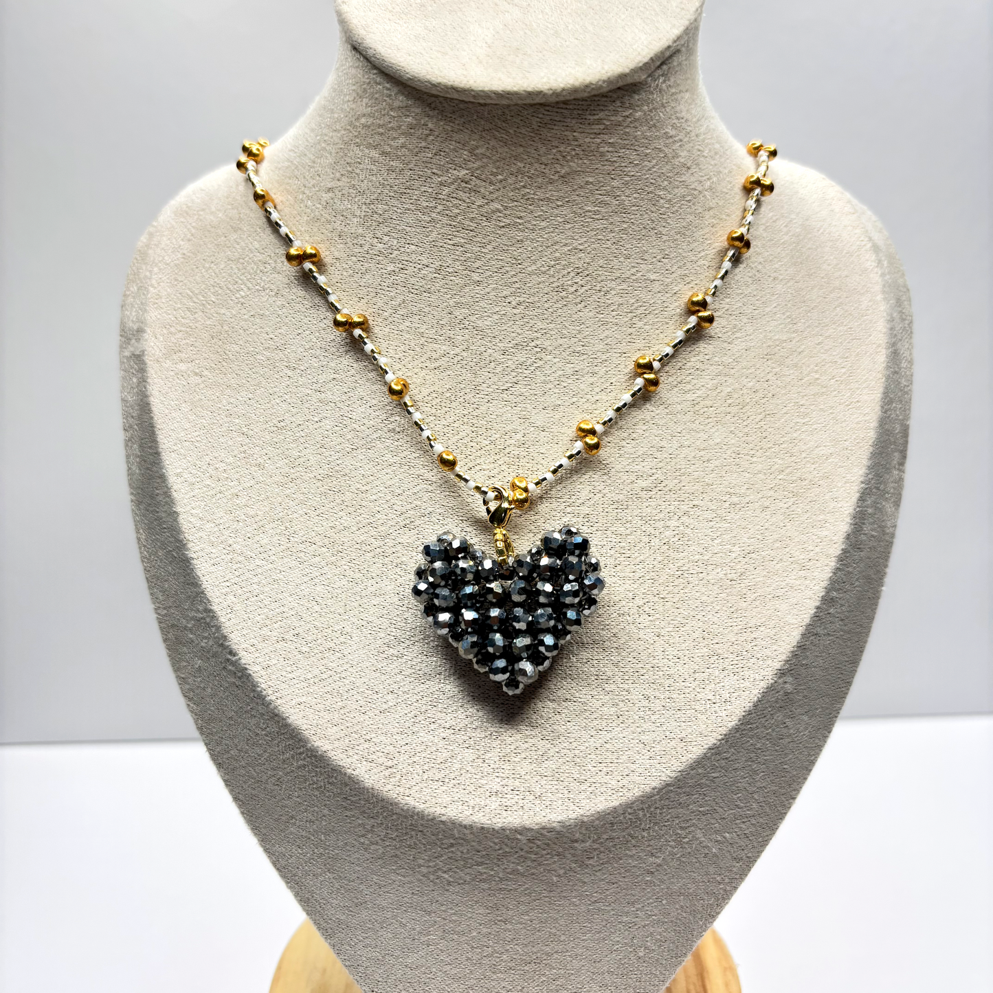 Necklace with a heart-shaped pendant on a mannequin bust against a plain background