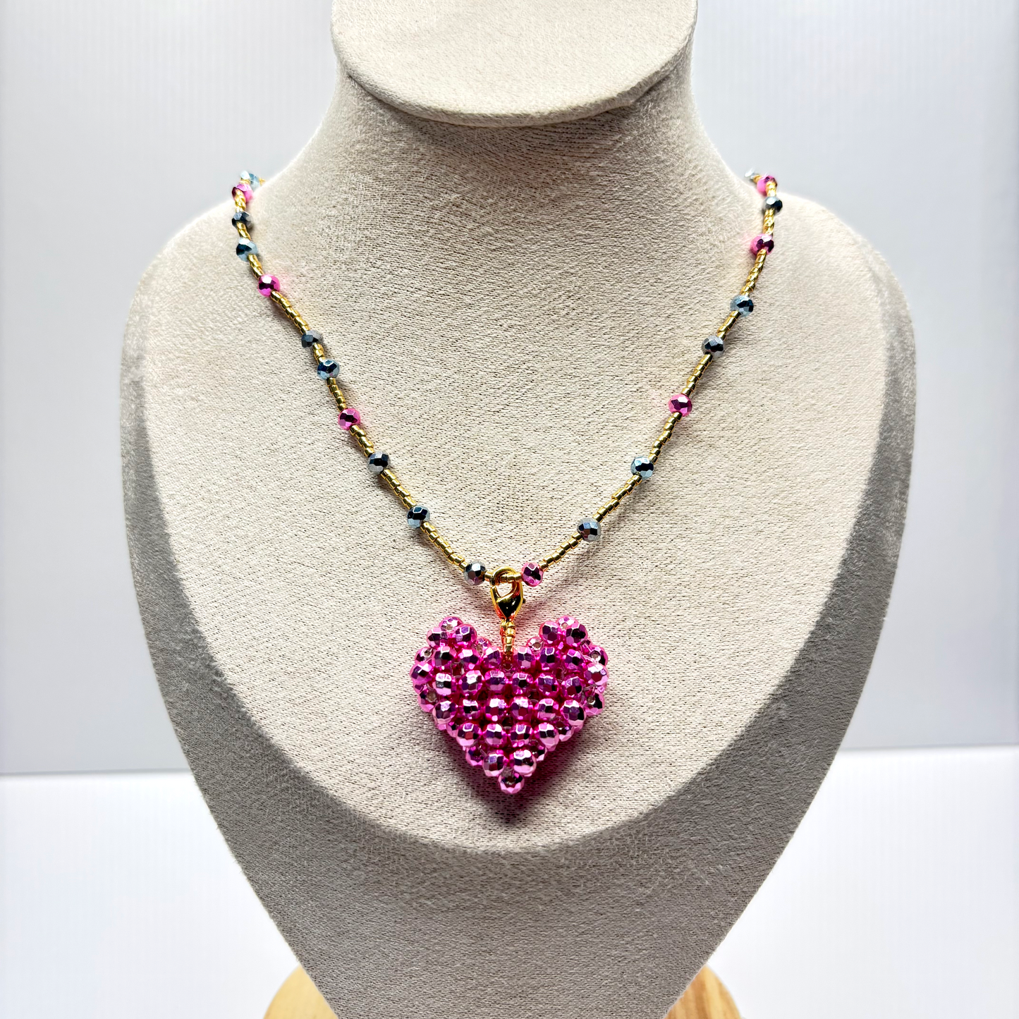 Necklace with a pink heart pendant on a mannequin bust against a white background