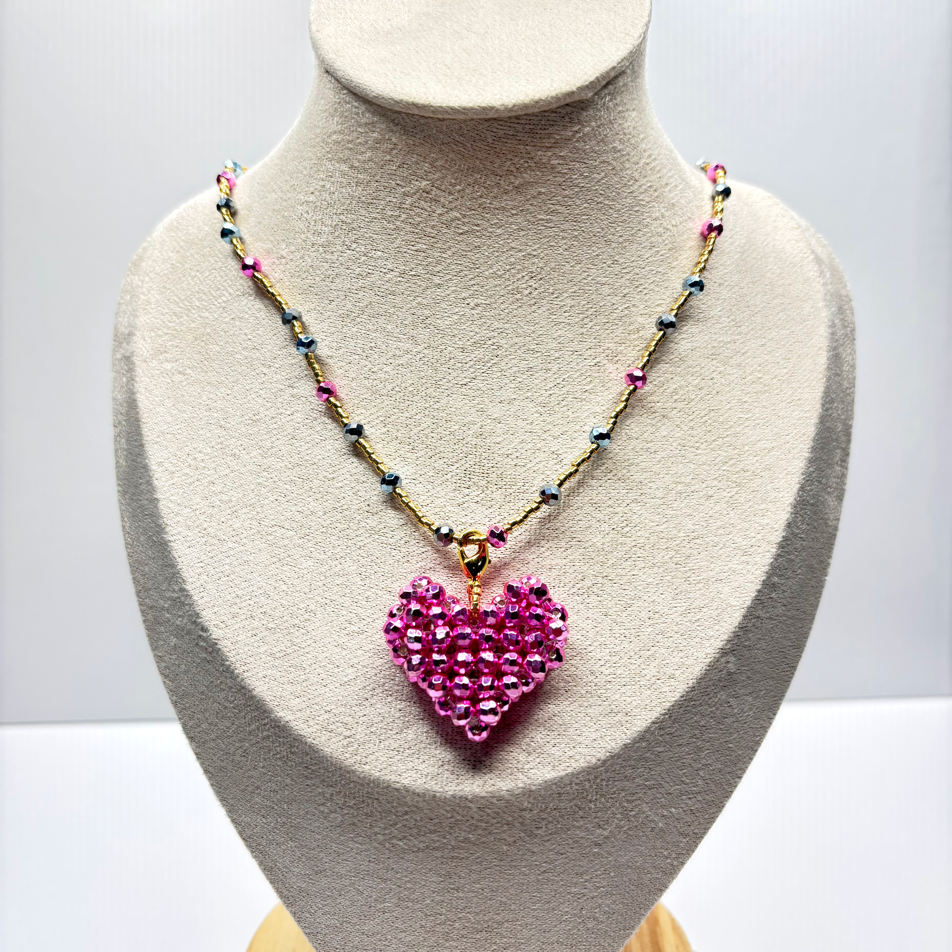 Necklace with a pink heart pendant on a mannequin bust against a white background