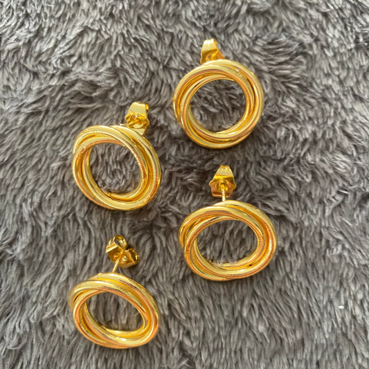 Set of gold hoop earrings on a gray textured surface