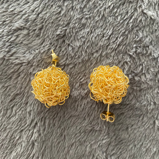 Pair of gold earrings on a gray textured surface
