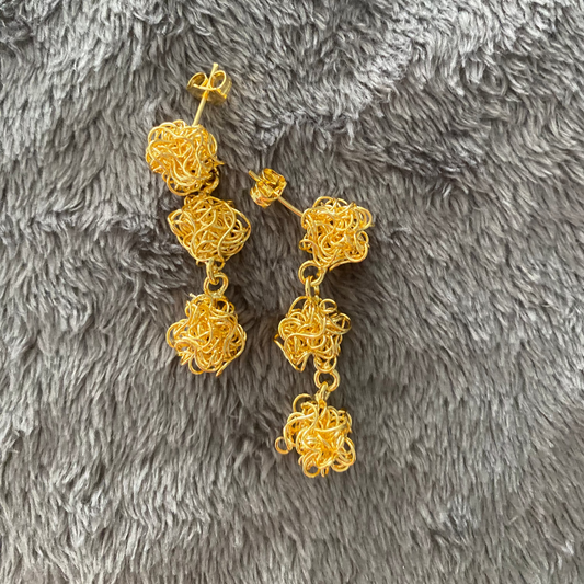 Gold earrings on a gray textured surface