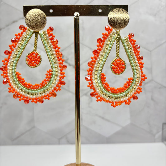 A pair of Amalia Drop Earrings featuring a gold top with black beaded chains hanging downwards, displayed on a stand.