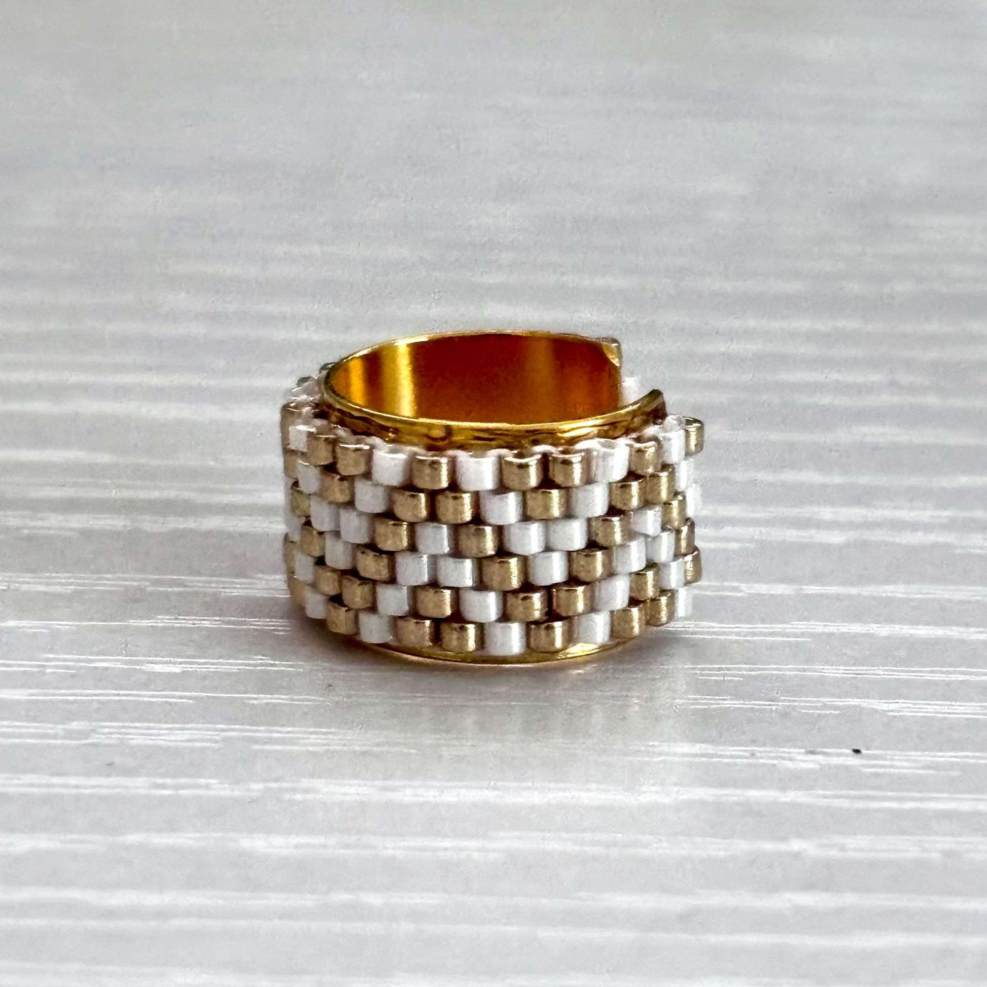 Stacked gold and silver ear cuff on a textured gray surface