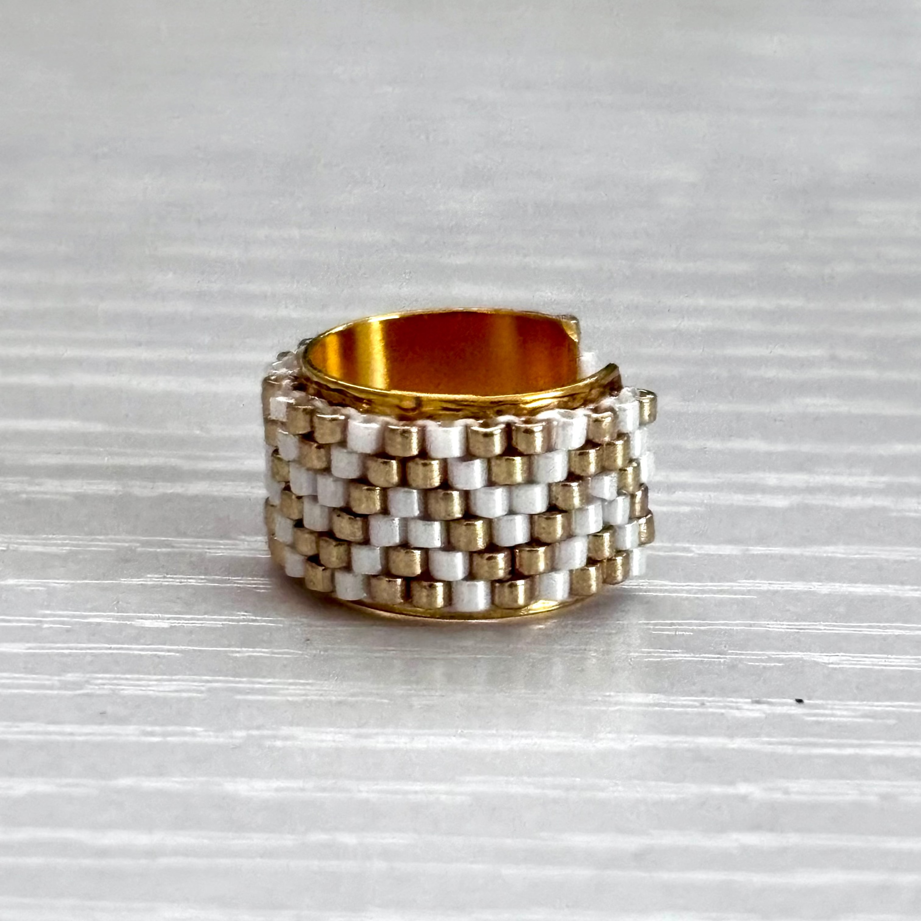 Stacked gold and silver ear cuff on a textured gray surface