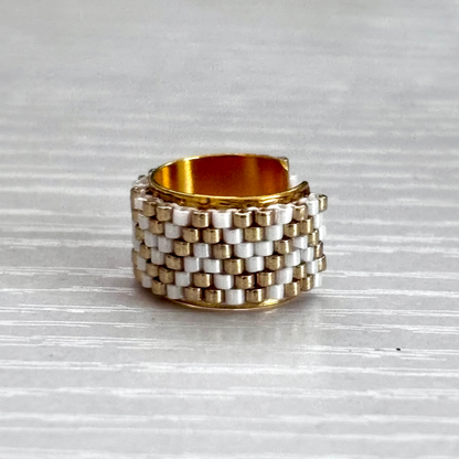 Stacked gold and silver ear cuff on a textured gray surface