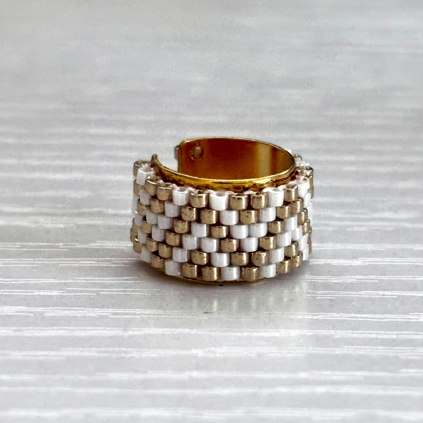 Stacked gold and silver ear cuff on a textured gray surface