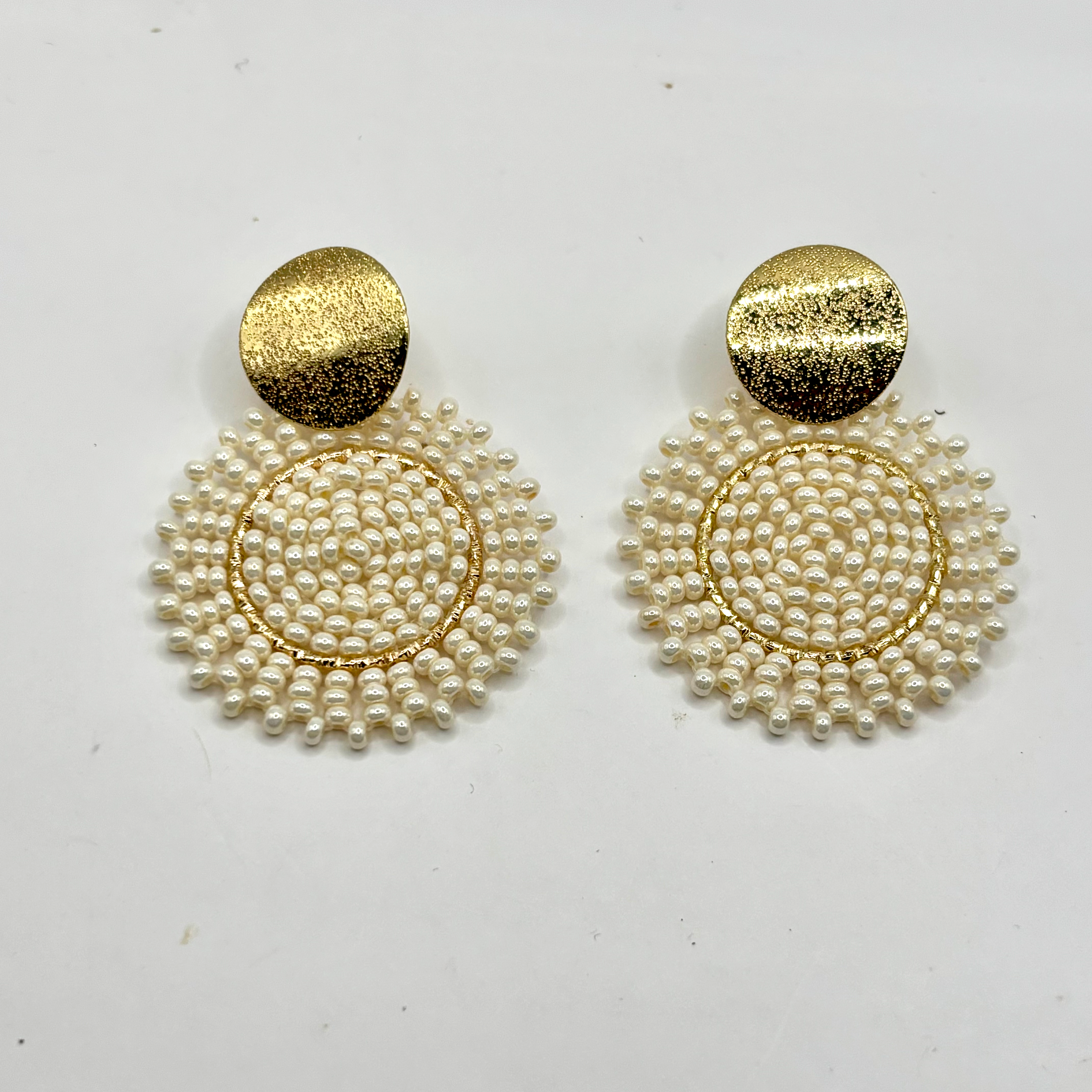 Pair of earrings with gold and pearl design on a white background