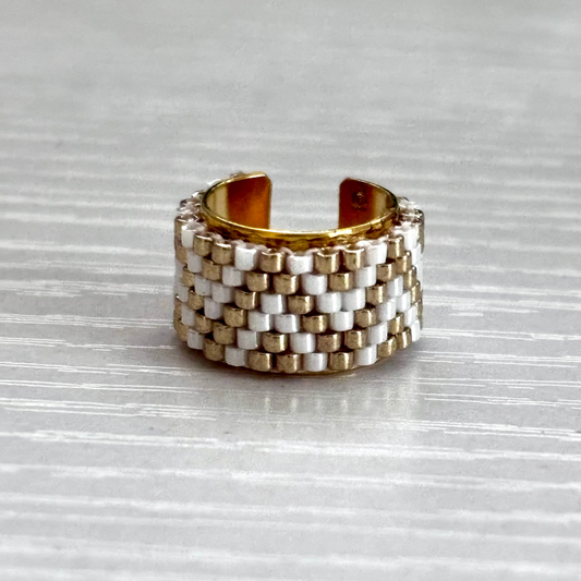 Stacked gold and silver ear cuff on a textured gray surface