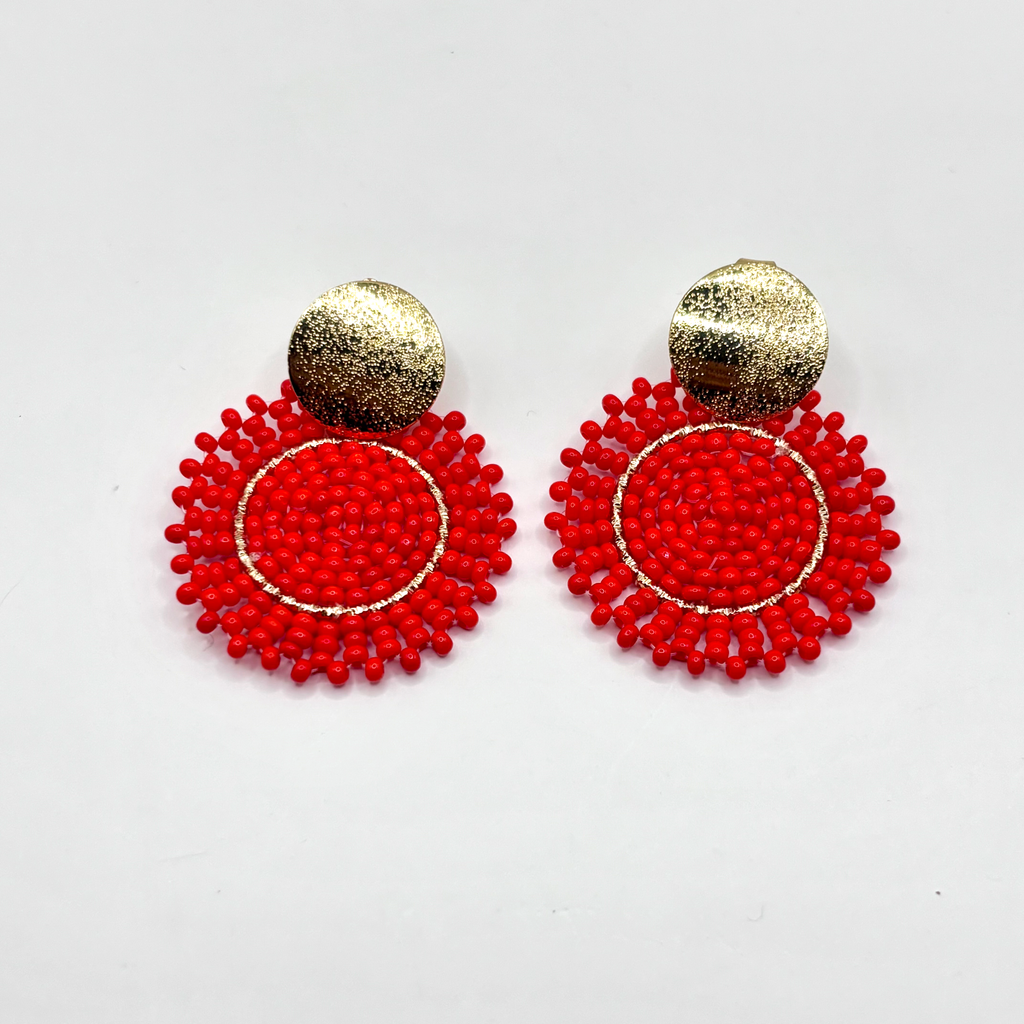 Red beaded earrings with gold spherical tops on a white background